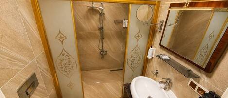 Baño con ducha, inodoro, lavamanos y espejo.