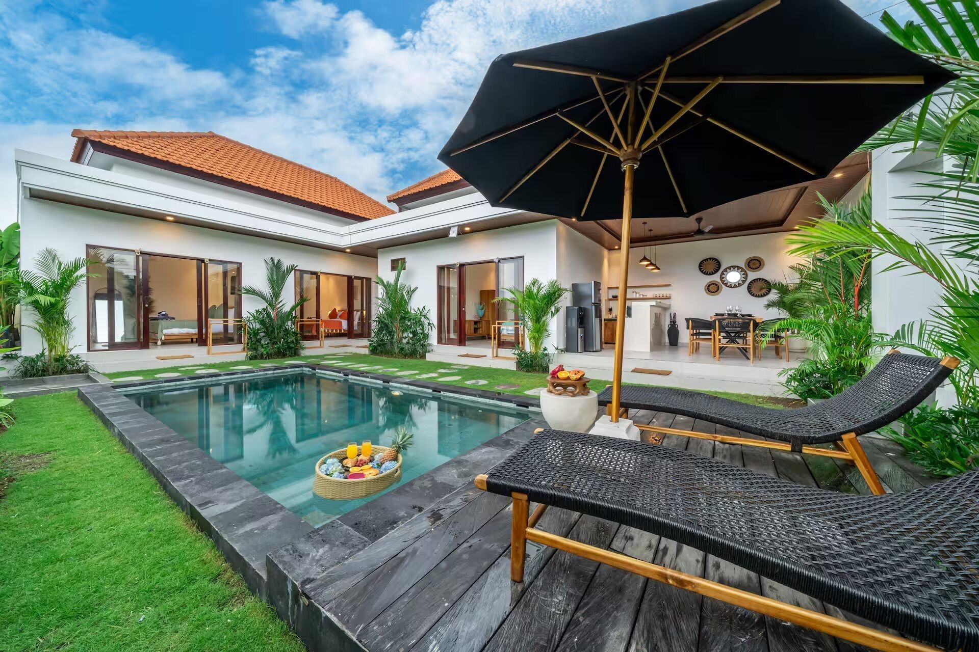 Ein modernes Haus mit Schwimmbad, Sitzgelegenheit im Freien und einem gepflegten Garten.