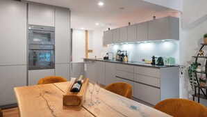 Una cocina moderna con electrodomésticos integrados, una mesa de comedor de madera y una isla con iluminación debajo de los armarios.
