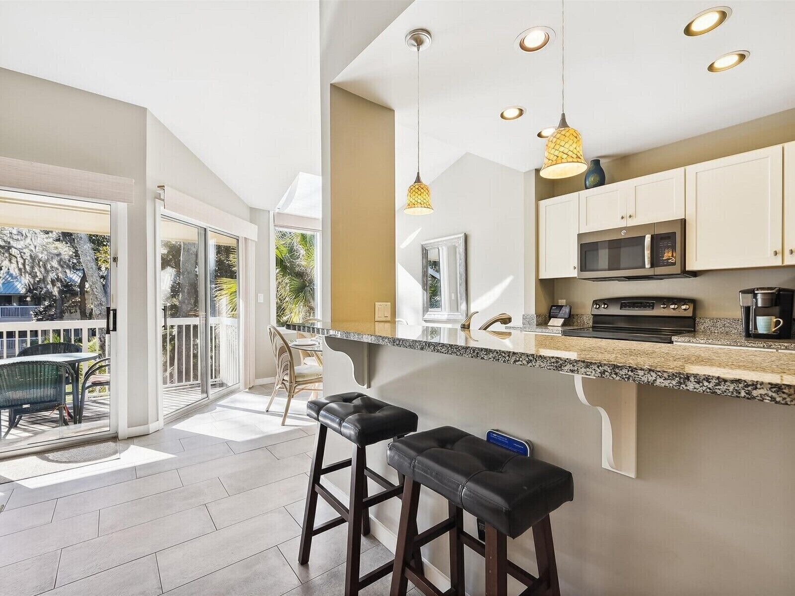 A modern kitchen with a large island, stainless steel appliances, and pendant lighting.