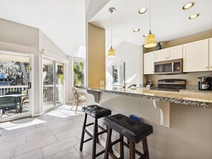A modern kitchen with a large island, stainless steel appliances, and pendant lighting. - Lush Lagoon Views | Steps to Sand, Pool & Golf! (Hilton Head Island)