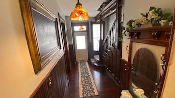 A hallway with a patterned rug, wooden doors, a staircase, and a decorative light fixture.