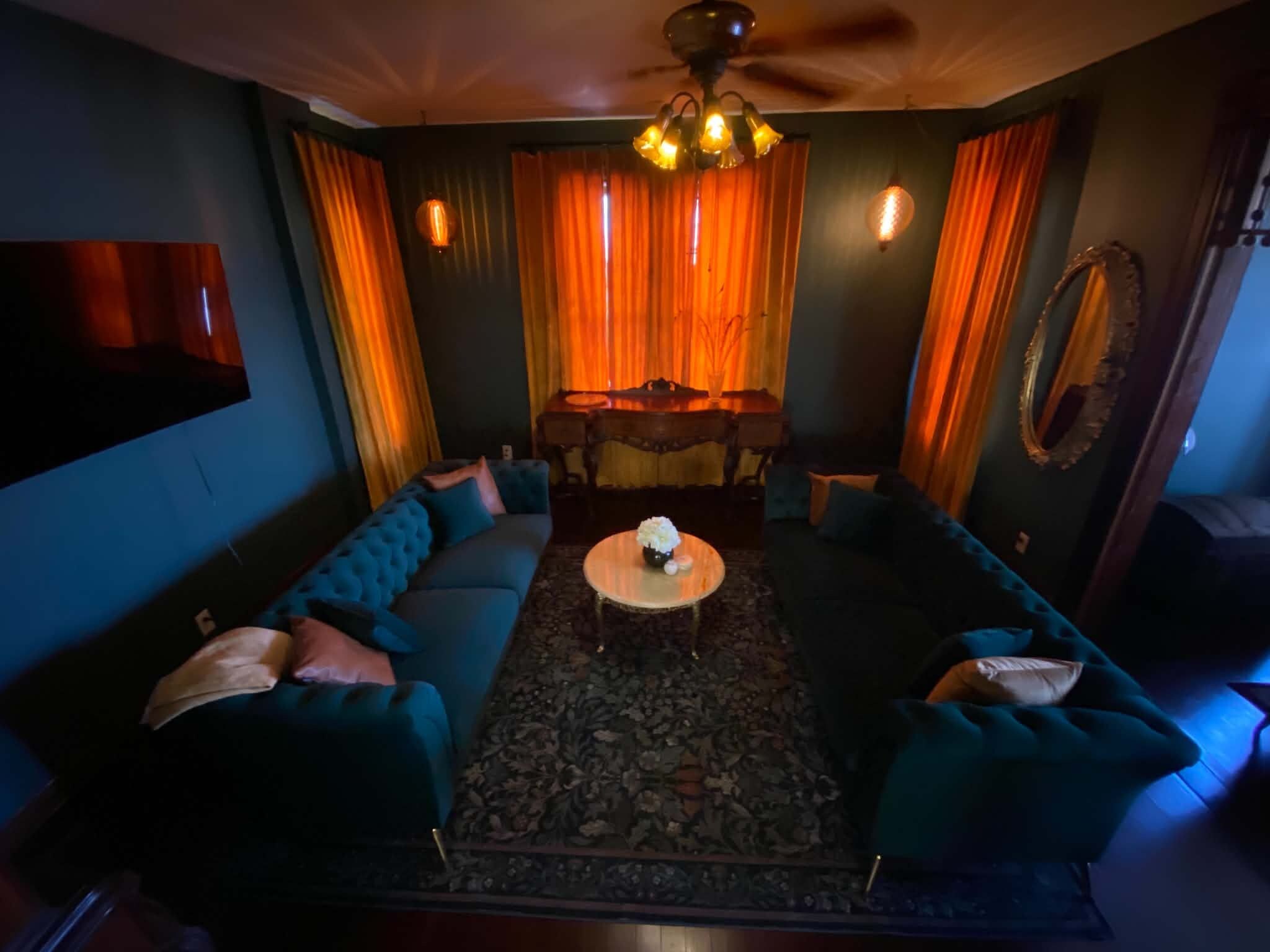 A room with a sectional sofa, a round coffee table, and a ceiling fan.