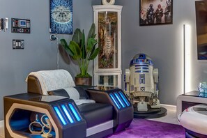 A modern living room with a massage chair, a Star Wars-themed sculpture, and a large aquarium. - Star Wars Immersive Home w/ Private Pool, Arcade, Theater, Themed Bedrooms (Kissimmee)