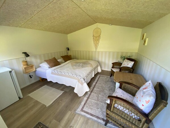 A bedroom with a bed, two bedside tables, a nightstand, a chair, a desk, and a hanging dreamcatcher. - 4 Star Holiday Home in Ansager (Ansager)