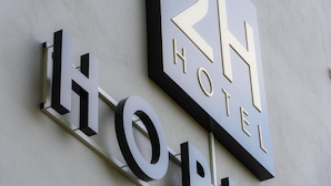 A hotel sign with the name '2H HOTEL' and the word 'HOTEL' below it.
