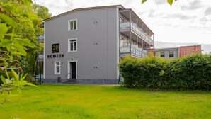 A 2H Horizon hotel with a grey facade, a balcony on the upper floor, and a well-maintained lawn in front.