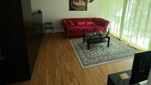 A living room with a red sofa, a coffee table, and a TV on a stand.