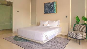 A modern hotel room with a large bed, a green chair, and a painting on the wall.