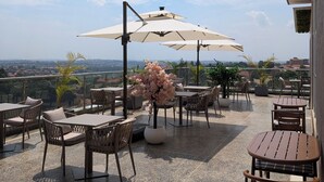 Une terrasse avec des sièges extérieurs, des parasols et une vue sur le paysage urbain.