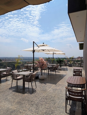 A terrace with outdoor seating, umbrellas, and a view of the cityscape.