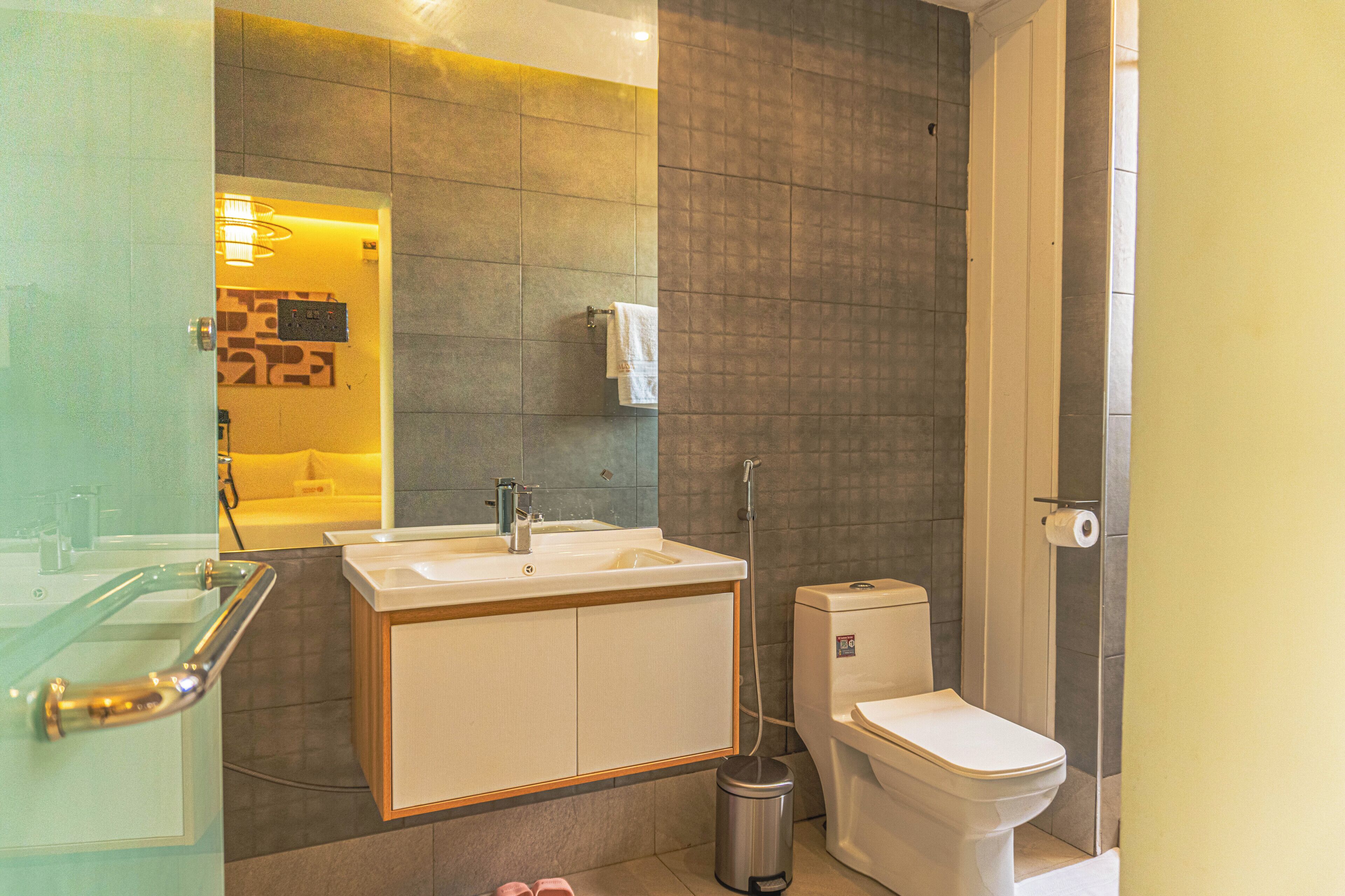 Een moderne badkamer met een douchecabine van glas, een witte wastafel en een toilet.