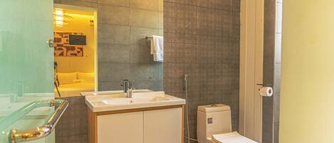 Un baño moderno con cabina de ducha de vidrio, un lavamanos blanco y un inodoro.