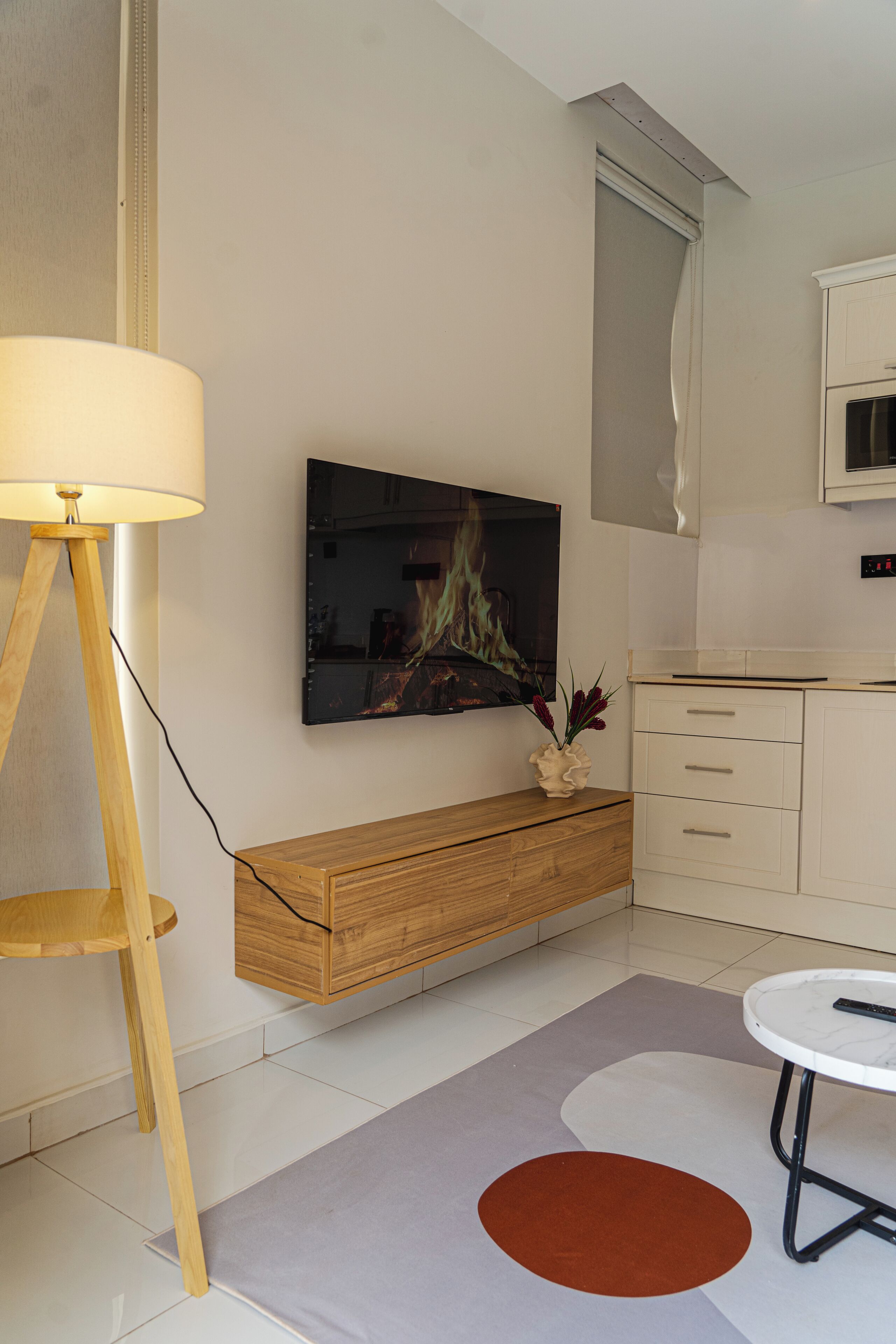 Ein modernes Wohnzimmer mit Flachbildfernseher, Holzschrank und rundem Tisch.