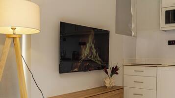 Ein modernes Wohnzimmer mit Flachbildfernseher, Holzschrank und rundem Tisch.