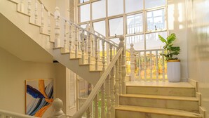 Un escalier avec des balustrades blanches et un pot de fleurs placé sur le palier.