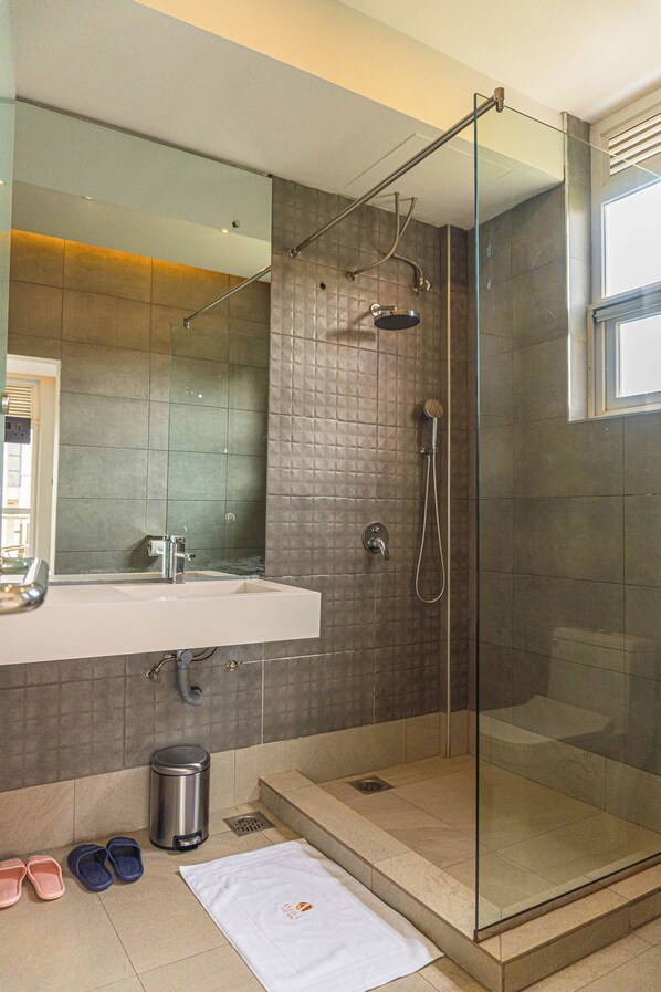 Un baño moderno con ducha envuelta en cristal, un espejo grande y un lavamanos.