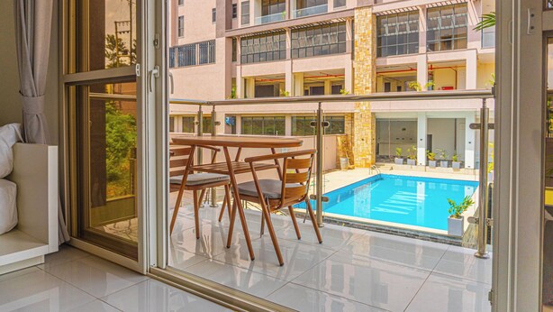 Un balcon avec une piscine, un canapé et une table avec des chaises.