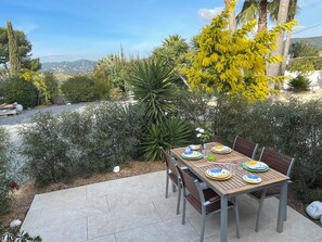 An outdoor dining area with a table set for four, surrounded by various plants and trees. - Superb T2 RDJ in quiet Sanary (Sanary-sur-Mer)