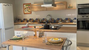 Uma cozinha moderna com bancada de madeira, eletrodomésticos de aço inoxidável e painel de fundo colorido.