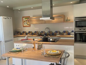 A modern kitchen with a wooden countertop, stainless steel appliances, and a colorful backsplash. - Superb T2 RDJ in quiet Sanary (Sanary-sur-Mer)