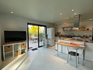 A modern kitchen with a TV, dining area, and sliding glass doors to a patio. - Superb T2 RDJ in quiet Sanary (Sanary-sur-Mer)