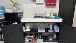 Una cocina compacta con microondas, pileta y estantes para guardar.