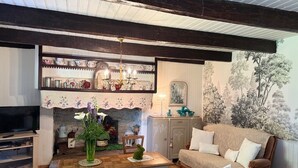 Un salon confortable avec une cheminée, un téléviseur et un coin repas comprenant une table et des chaises.
