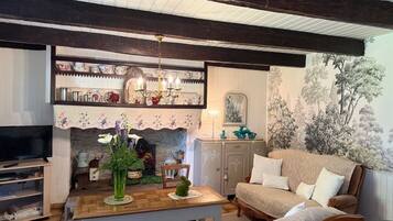 A cozy living room with a fireplace, a television, and a dining area with a table and chairs.