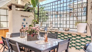 An outdoor dining area with a table, chairs, potted plants, and a decorative lantern.