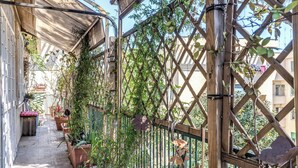 A narrow outdoor corridor with a wooden lattice fence, potted plants, and a tiled floor.