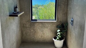 Ein Badezimmer mit großem Fenster, einem Blumentopf und einer Duschkabine.