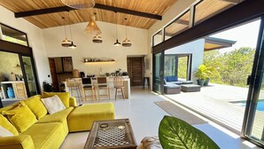 Ein modernes Interieur mit einem gelben Sofa, einem Couchtisch und großen Grünpflanzen.