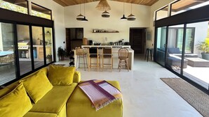 Ein modernes Interieur mit einem gelben Sofa, einem Essbereich und einer Küche.