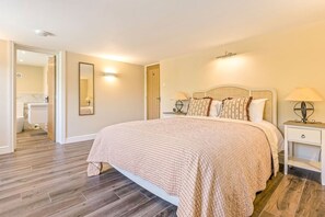 A bedroom with a large bed, a nightstand with a lamp, a mirror, and a door leading to a bathroom. - Chestnut Cottage in Bix (Bix)