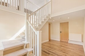 Eine Treppe mit weißen Geländern führt zu einer oberen Etage, ein Holztür und ein Heizkörper an der Wand.