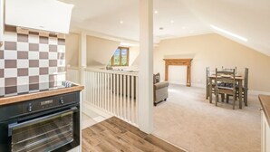A spacious loft with a kitchen, dining area, and a fireplace. - Chestnut Cottage in Bix (Bix)