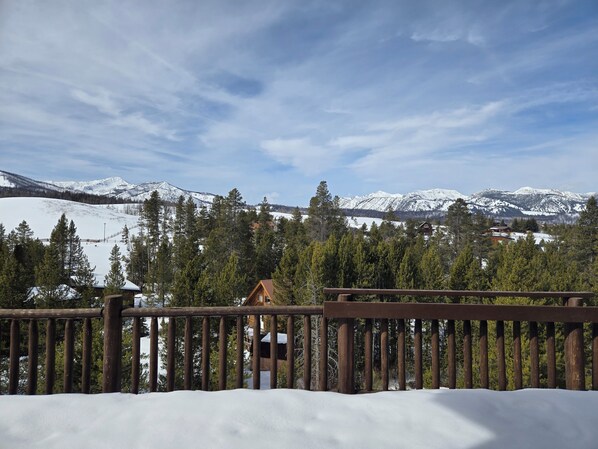 A snow-covered mountain landscape with a wooden fence and a cabin in the foreground.