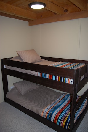 A bunk bed with a lower bunk and a top bunk, both with patterned bedding.