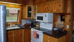 A kitchen with wooden cabinets, a stainless steel sink, a microwave, and a stove.