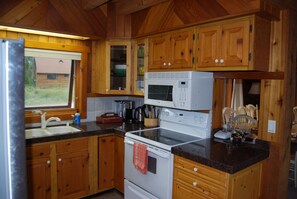 A kitchen with wooden cabinets, a stainless steel sink, a microwave, and a stove.