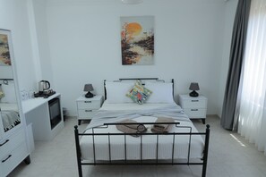 Un dormitorio con cama, mesitas de noche, un escritorio y un cuadro en la pared.