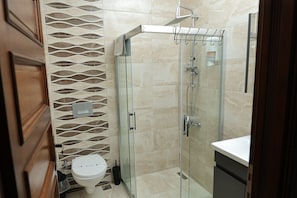 Un baño moderno con cabina de ducha de vidrio, inodoro y lavamanos.