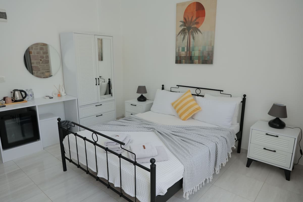 Une chambre à coucher avec un lit, des tables de chevet, une armoire, un miroir et un tableau accroché au mur.