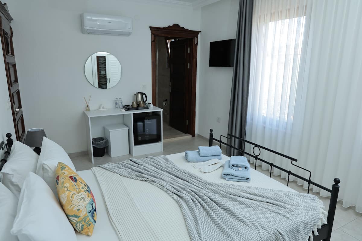 Une chambre à coucher comprenant un lit, une table de chevet, un miroir et un téléviseur fixé au mur.