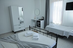 A hotel room with a bed, a bedside table, a wardrobe, a mirror, a TV, and a window with curtains. - Adena Pansiyon (Küçükköy)