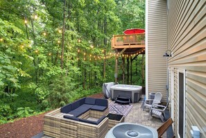 Un jardin avec un jacuzzi, un espace salon extérieur et des guirlandes lumineuses.
