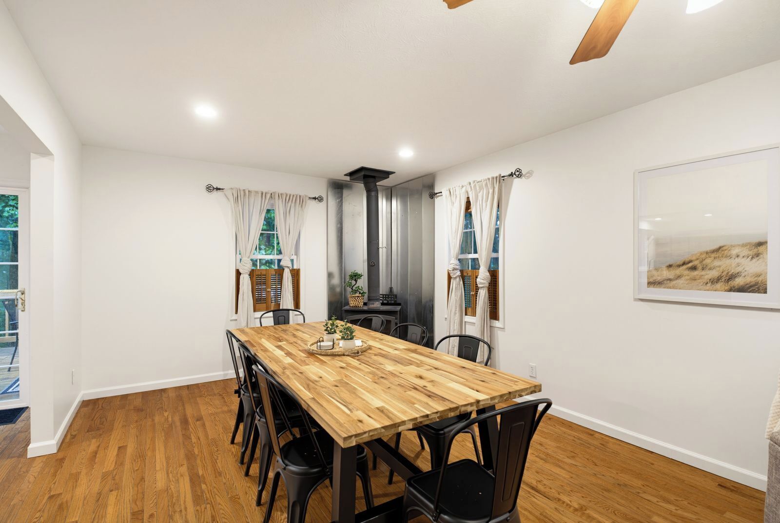 A dining area with a wooden table, black chairs, and a view of the kitchen through a glass partition.