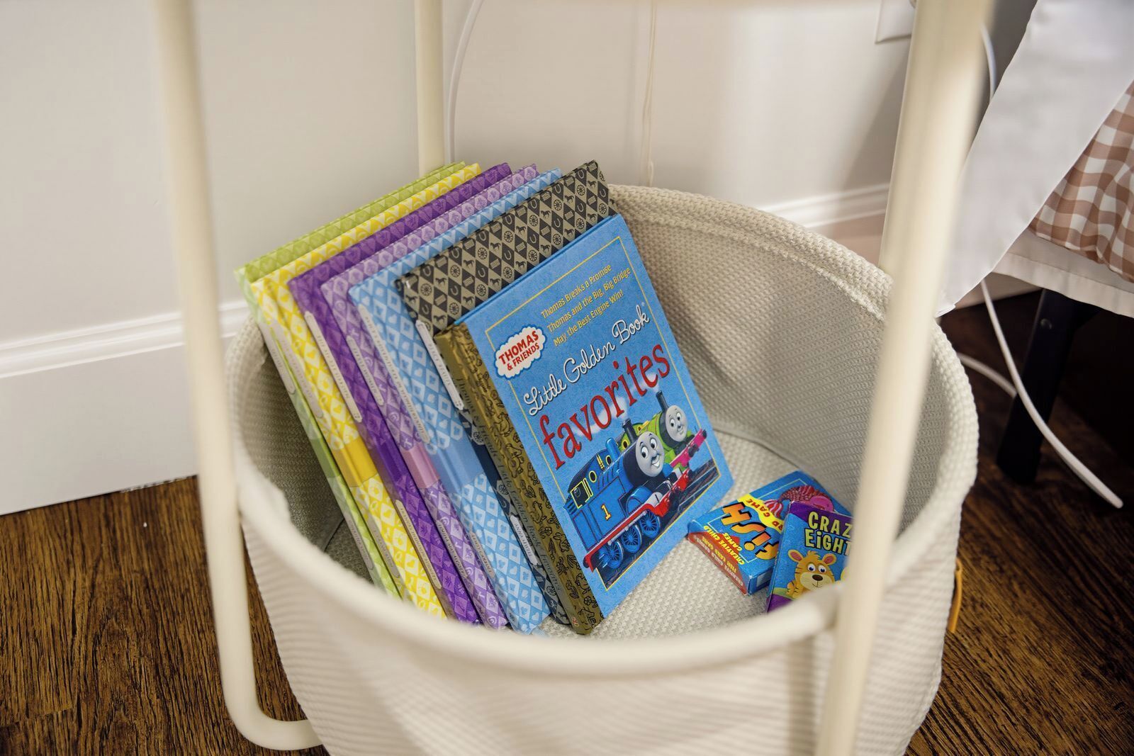 Un panier blanc contenant des livres, dont un livre de la série « Thomas et ses amis ».
