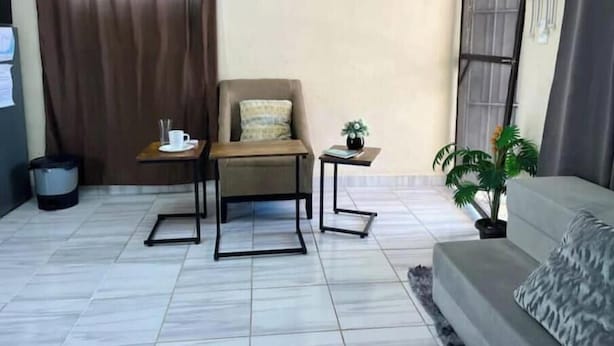 A small living area with a sofa, a chair, a small table with a cup, a trash bin, and a potted plant. - Apartment with Wi-Fi, A/C, and parking—near downtown and the boulevard (Chetumal)